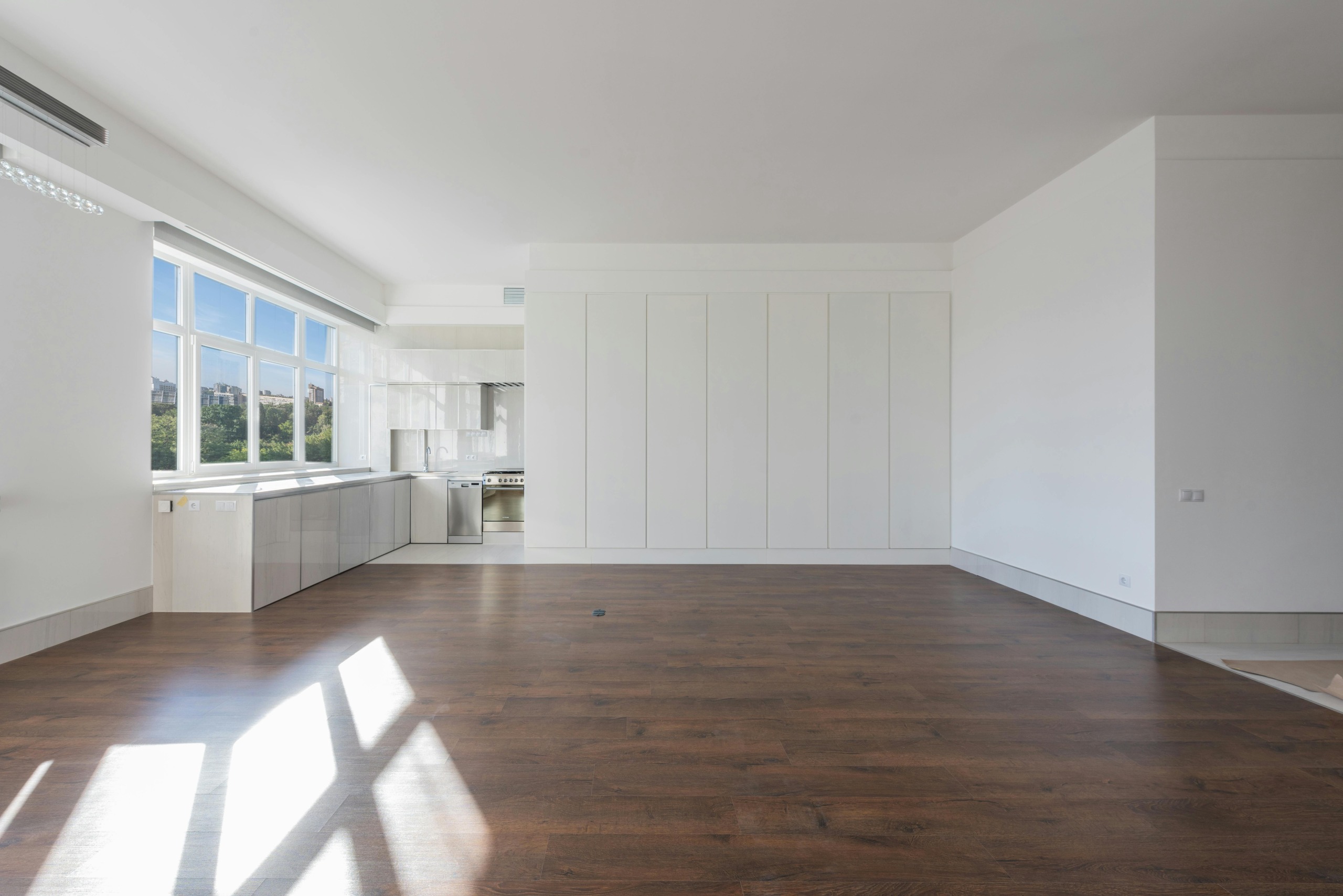 Bright and spacious modern kitchen interior featuring wooden floors and white cabinetry.